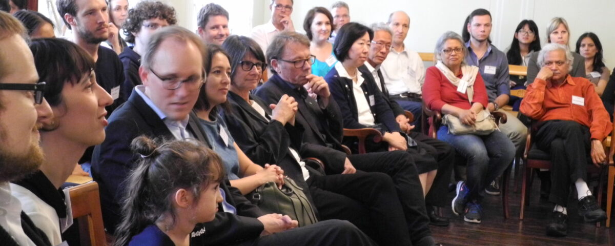 Participants of the network meeting are seated on chairs, in a semi-open circle facing a presentation area.