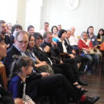 Participants of the network meeting are seated on chairs, in a semi-open circle facing a presentation area.
