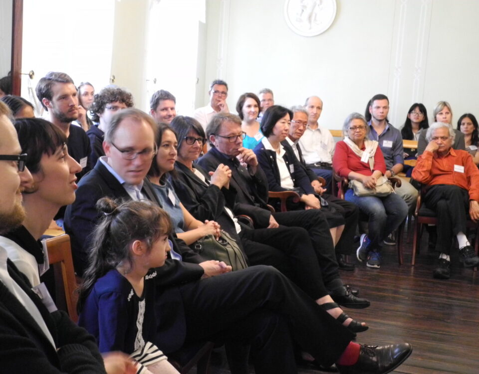 Participants of the network meeting are seated on chairs, in a semi-open circle facing a presentation area.