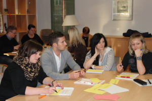 Staff from Leipzig University sitting around a table in front of worksheets on interculturality